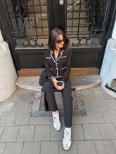 a lady wears a black tweed jacket with black pants and sneakers